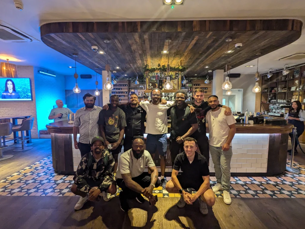 group-of-men-standing-and-kneeling-in-front-of-a-bar-smiling-in-a-warmly-lit-room-during-a-gathering