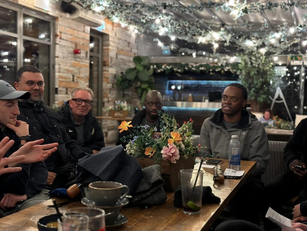 group-of-men-around-table-with-flowers-and-drinks-in-cozy-setting