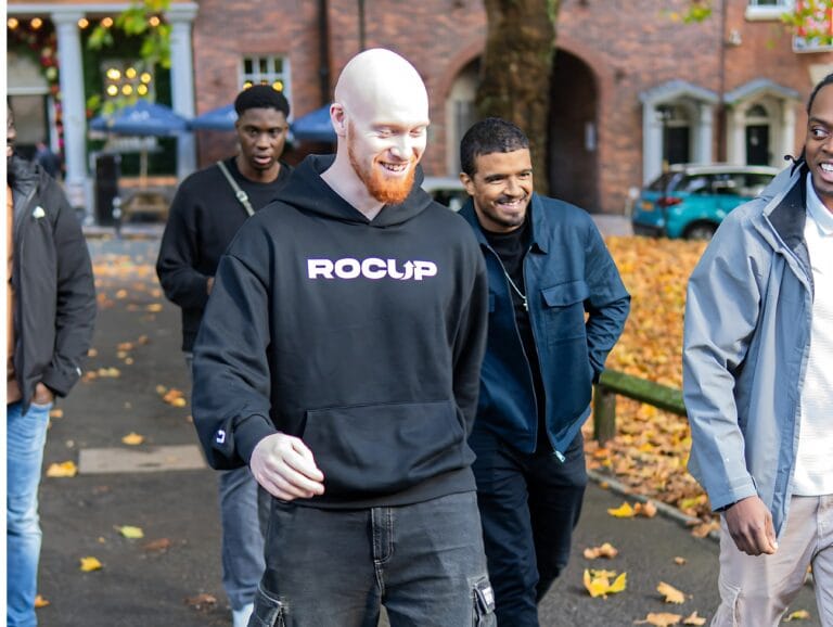 group-of-people-walking-outdoors-on-autumn-path-main-focus-on-smiling-man-with-red-beard-in-black-rocup-hoodie