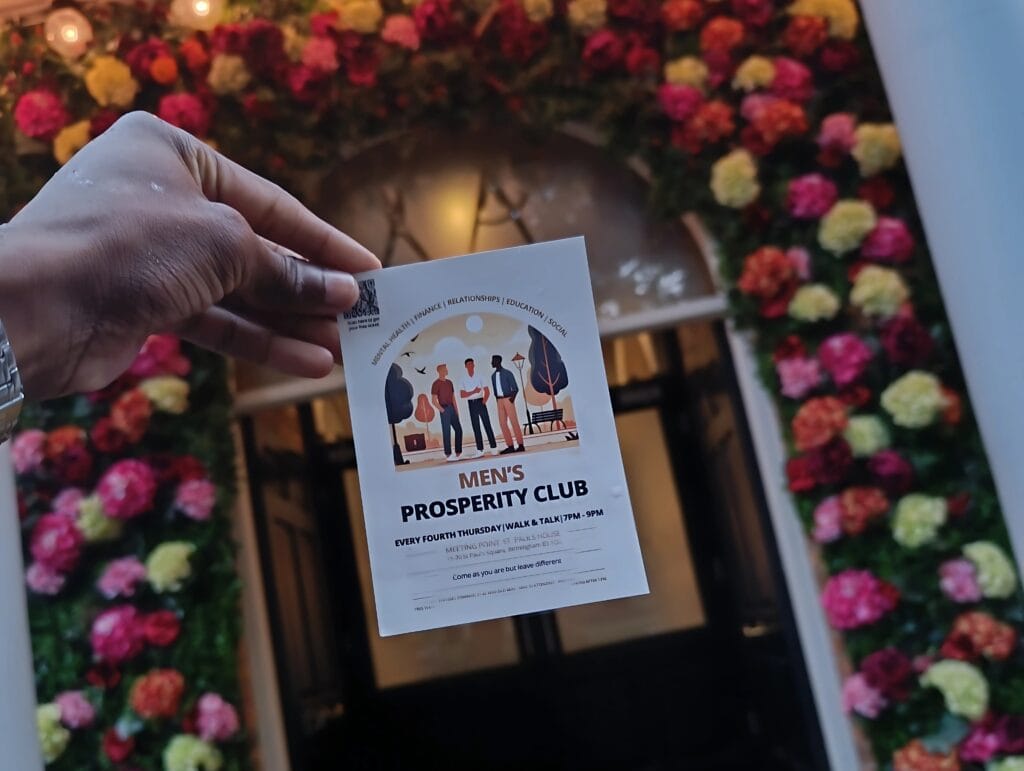 hand-holding-mens-prosperity-club-flyer-with-flower-decorated-entrance-in-background