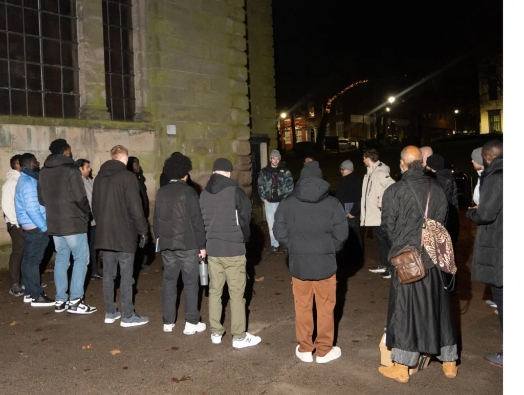 A-group-gathers-outside-a-historic-building-at-night-for-an-MPC-event-part-of-Season-2-Session-3-Relationships