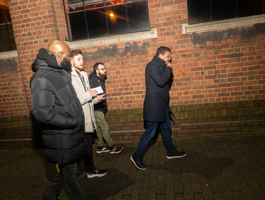 A-group-of-four-people-walking-at-night-with-a-brick-wall-in-the-background-possibly-during-Season-2-Session-1-Mental-Health