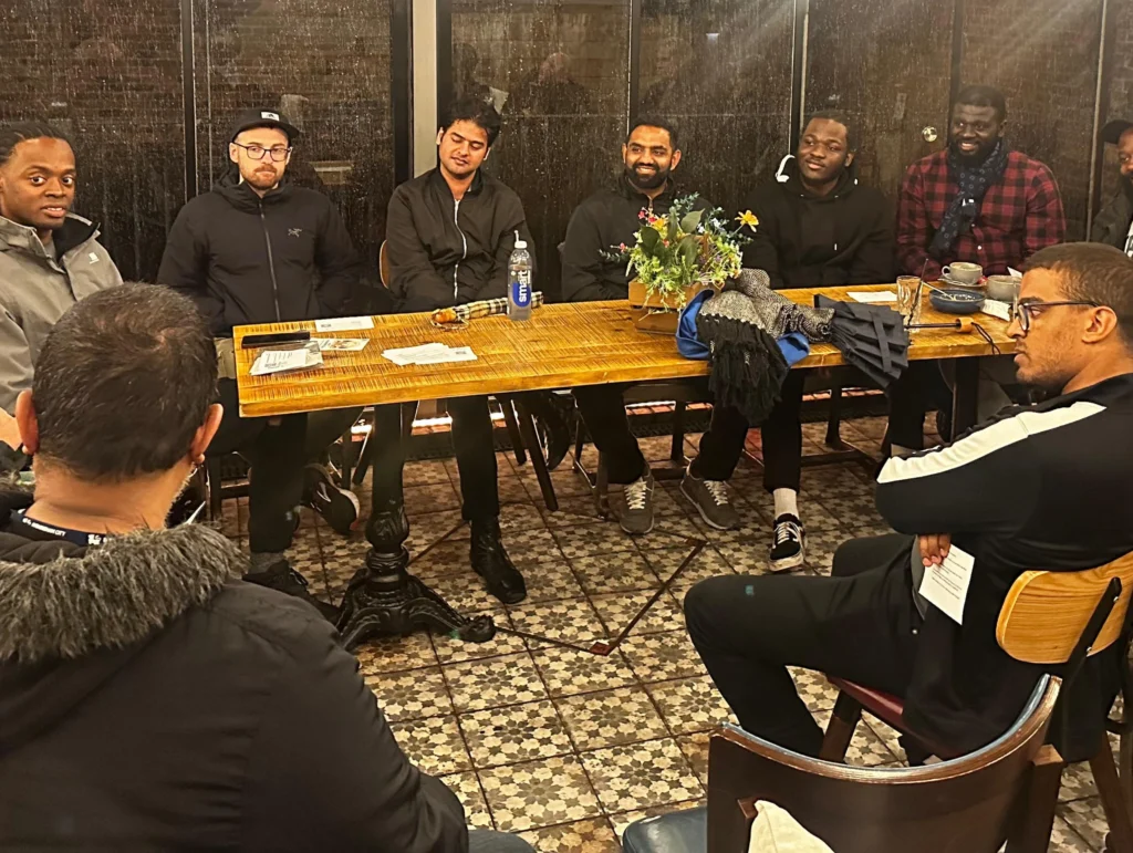 A-group-of-men-sit-around-a-table-engaged-in-a-discussion-during-an-MPC-event-Season-2-Session-1-Mental-Health