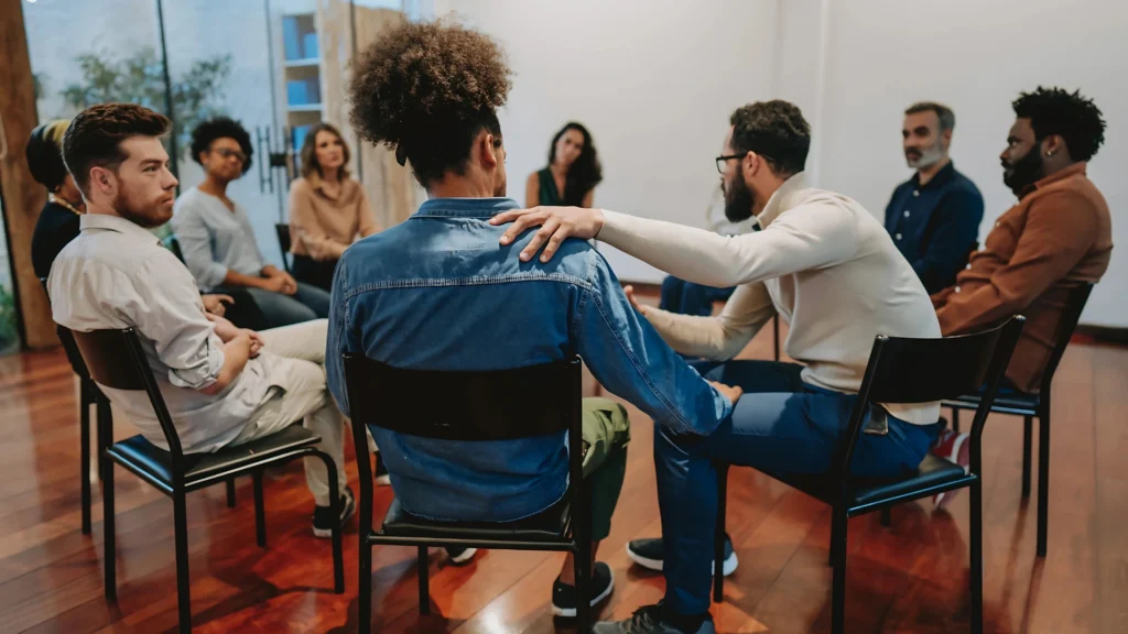 A-group-of-people-sitting-in-a-circle-during-a-support-group-session-with-one-person-comforting-another-overcoming-social-anxiety