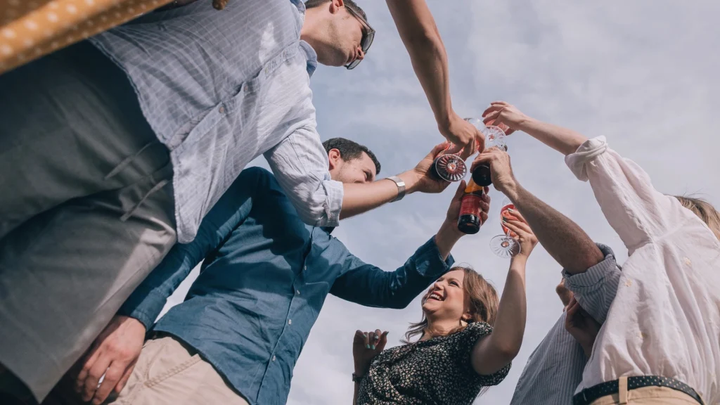 A-group-raises-glasses-in-celebration-under-the-sun-symbolizing-joy,-social-connections,-and-societal-norms-around-celebrations