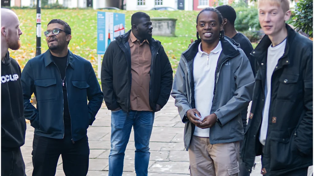 A-MPC-group-walking-and-talking-outdoors-on-a-leafy,-paved-walkway