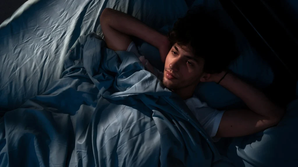 a-person-lying-in-bed-with-a-thoughtful-expression-dim-lighting-creating-a-reflective-and-moody-atmosphere-possibly-indicative-of-Seasonal-Affective-Disorde