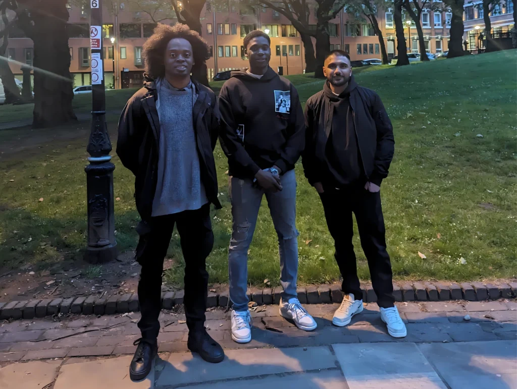 Three-people-posing-together-outside-in-a-park-during-evening-hours.