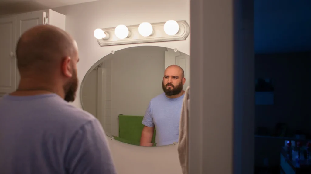 A-man-stands-reflecting-in-the-mirror-symbolizing-the-sexual-link-between-self-esteem-and-personal-image
