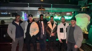 MPC-members-pose-together-at-a-night-out-event-with-Walk-and-Talk-promotion-in-the-background-at-a-casual-venue