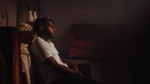 Man-sitting-in-dark-room-appearing-thoughtful-or-overwhelmed-with-stress-highlighting-the-mental-health-crisis