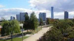 Walkway-in-London-park-surrounded-by-trees-and-modern-buildings-with-clear-blue-sky