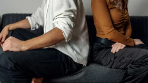 A-couple-sitting-apart-on-a-couch-showing-emotional-distance-after-infidelity