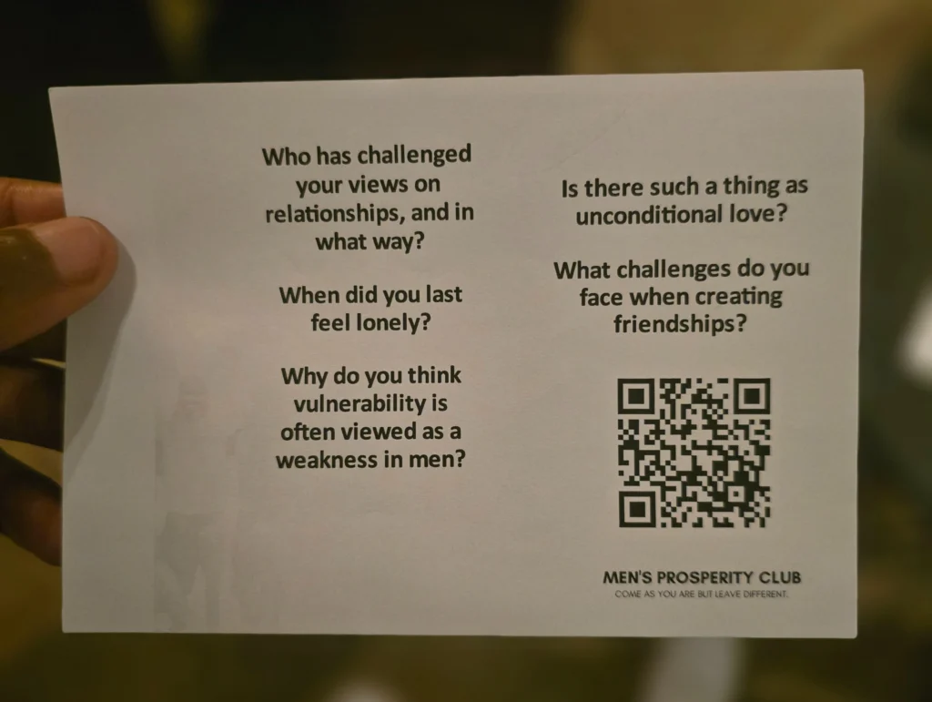 A-hand-holding-a-card-with-thought-provoking-questions-related-to-relationships-and-vulnerability-for-the-Mens-Prosperity-Club.