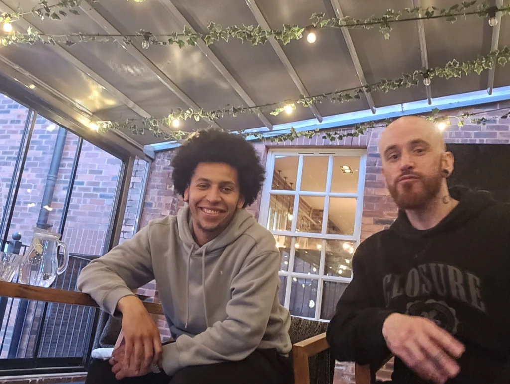 A-group-of-people-in-a-circle,-sitting-and-discussing-various-topics-while-reading-or-engaging-in-conversation,-with-some-people-holding-papers