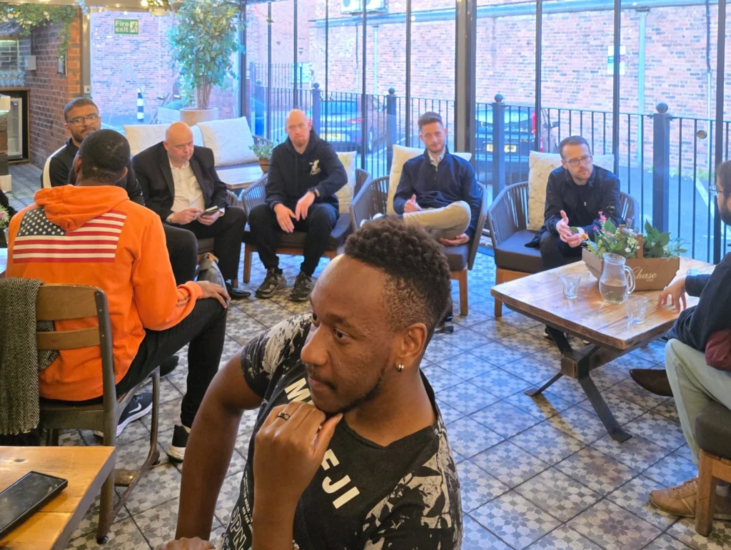 A-group-of-people-sitting-in-a-casual-meeting-space,-engaged-in-conversation,-with-some-people-looking-attentive-while-others-are-more-relaxed