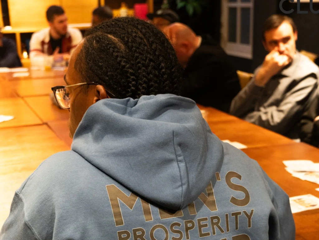 A-person-wearing-a-blue-'Men's-Prosperity-Club'-hoodie-in-a-Health-&-Fitness-club-setting-1