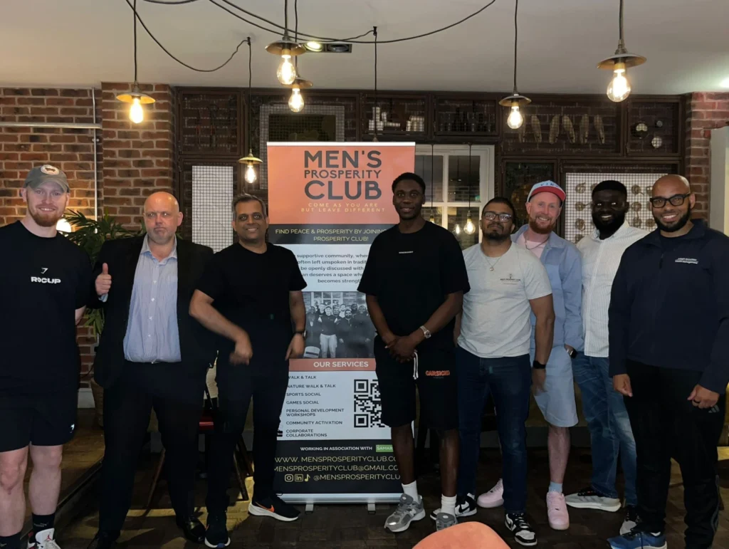 Group-photo-of-Mens-Prosperity-Club-members-with-a-banner-and-the-logo-in-the-background.