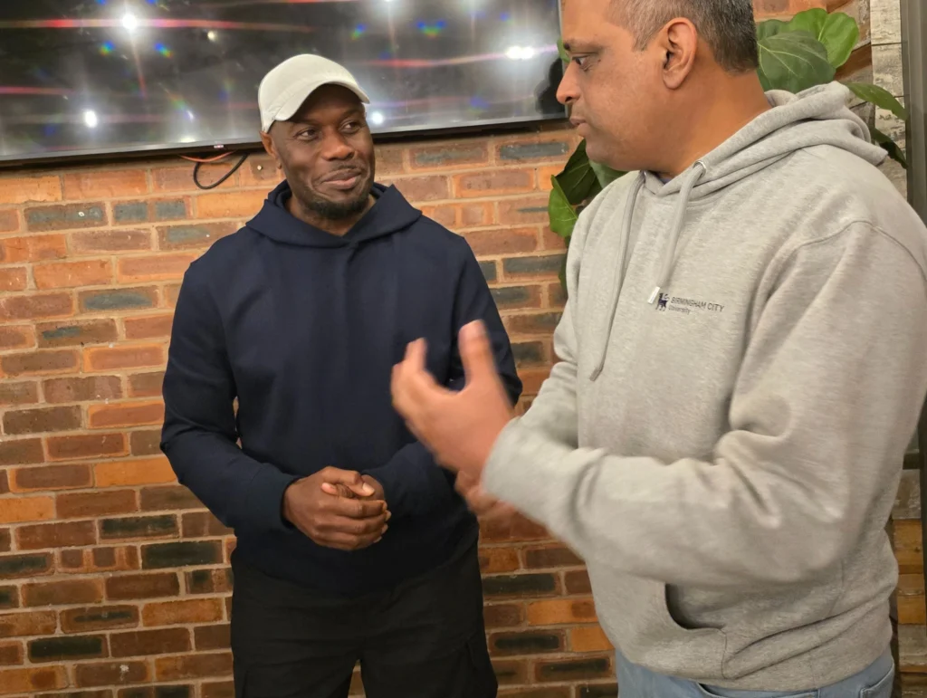 Two-individuals-talking-at-a-networking-event-with-one-gesturing-while-the-other-listens