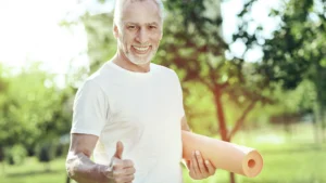 An-elderly-man-smiling-and-holding-a-yoga-mat-demonstrating-the-positive-effects-of-quality-sleep-on-physical-well-being