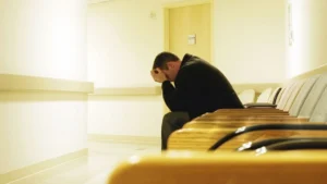 A-man-sitting-in-a-waiting-room-head-down-symbolizing-stress-and-mental-health-struggles-on-World-Mental-Health-Day-2025