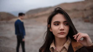 A-woman-looking-pensive-with-a-man-blurred-in-the-background-symbolizing-emotional-aftermath-in-Mens-Mental-Health-After-Breakup