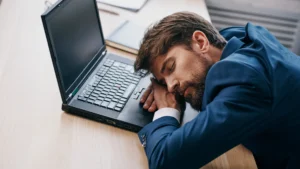 Burnt-out-man-suffering-from-work-related-illness-leaning-on-laptop