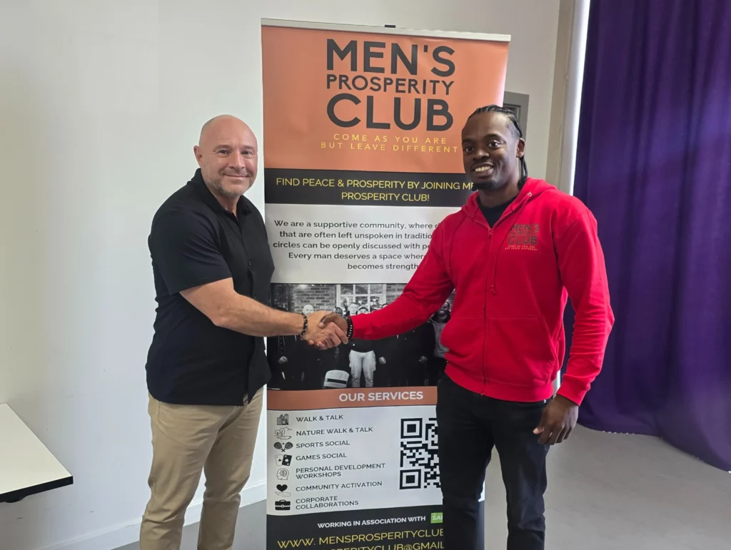 John-Kenny-and-a-participant-posing-for-a-photo-in-front-of-the-Men's-Prosperity-Club-banner-after-the-PD-workshop