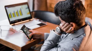 Man-procrastinating-at-work-with-laptop-and-phone